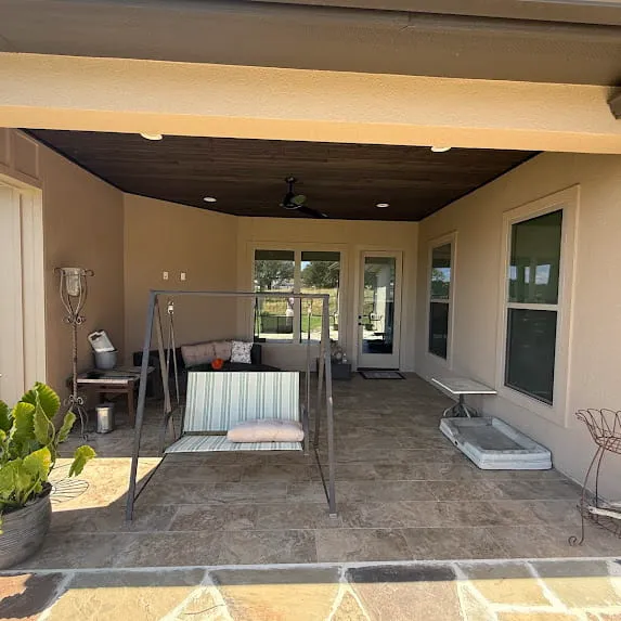 Covered patio with beige exterior walls, a wood ceiling, and a porch swing
